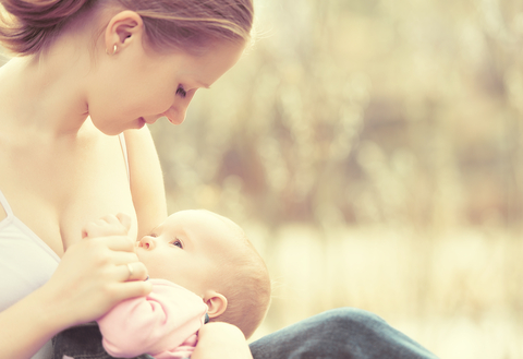 Mother and baby breastfeeding outdoors in summer