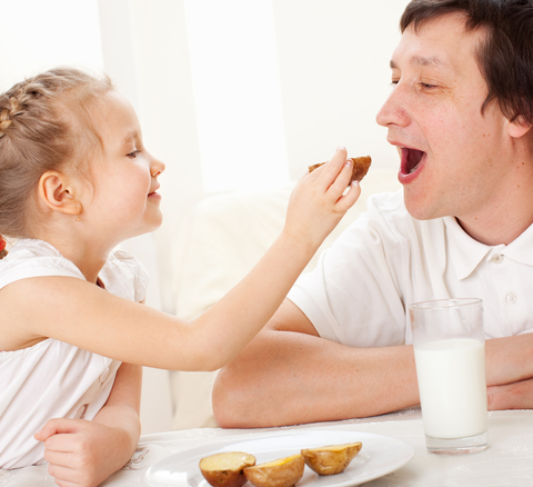 Young girl feeding her father breakfast